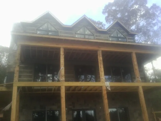 Dormers and porch framing on a large log home under construction — Roof Coating work by our crew in Henrico
