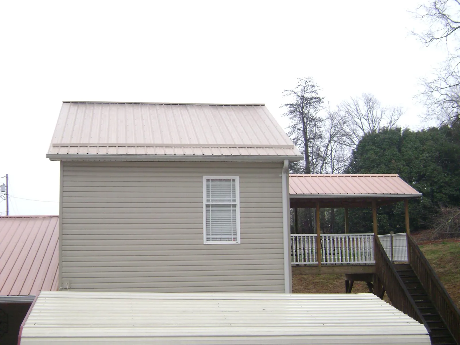 Tan metal roofs on a two story addition and attached porch, from a Roof Replacement job in Henrico