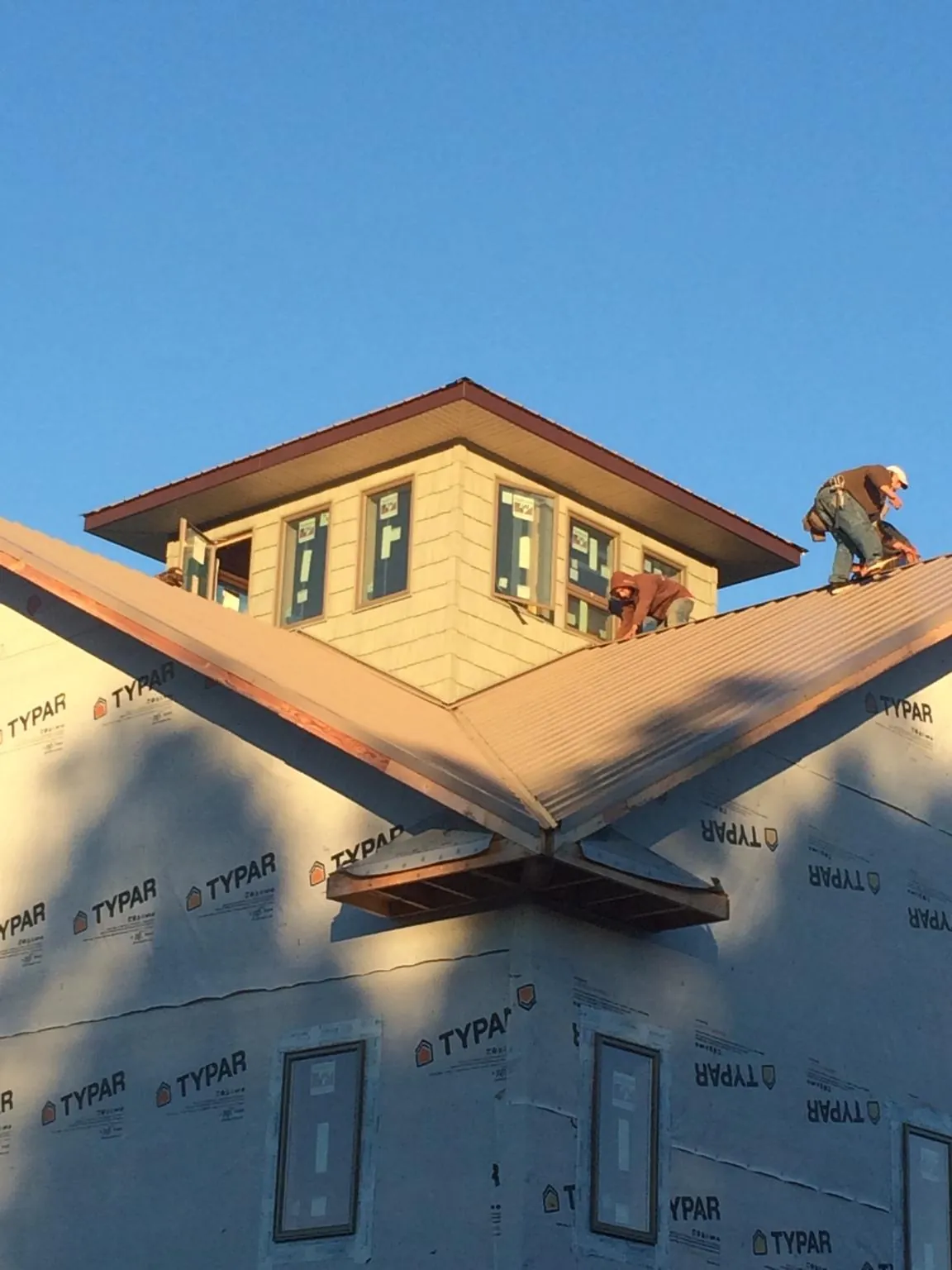 Roofers working around a rooftop cupola on a new metal roof at sunset — Roof Waterproofing in Henrico by Roofing Brothers